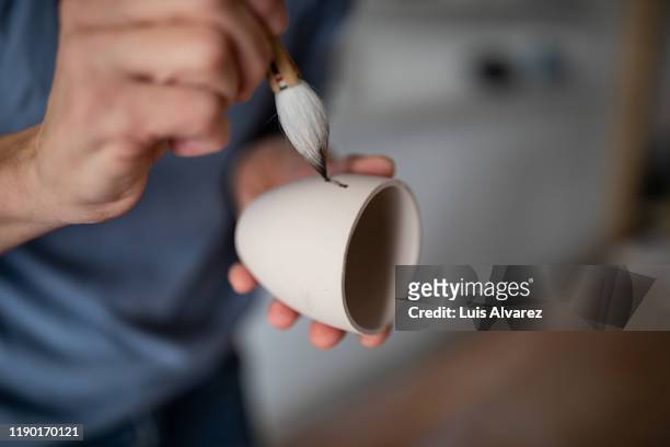 pottery artist painting a cup - artist painting stock-fotos und bilder