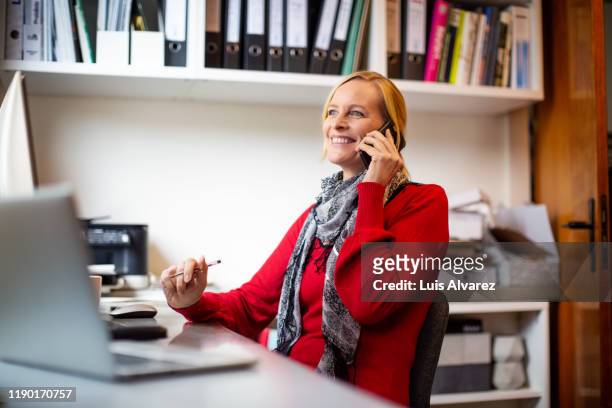 smiling female owner talking on phone in workshop - red office chair stock pictures, royalty-free photos & images