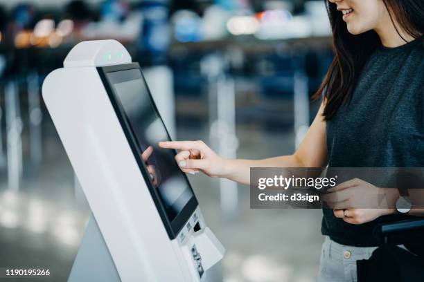 young asian woman travelling by plane and doing self check in at the airport using a machine - check in airport stock pictures, royalty-free photos & images