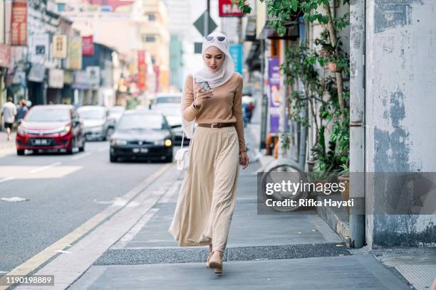 hijab businesswomen using phone while walking - kuala lumpur street stock pictures, royalty-free photos & images