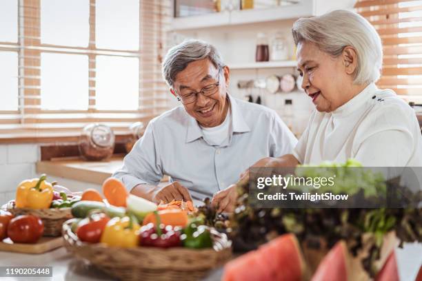 senior asian couple cooking together in kitchen - healthy lifestyle senior stock pictures, royalty-free photos & images