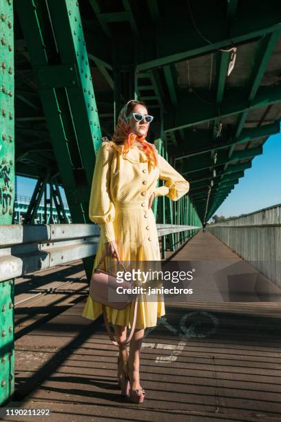 woman in yellow dress posing on the industrial bridge - yellow retro dress stock pictures, royalty-free photos & images