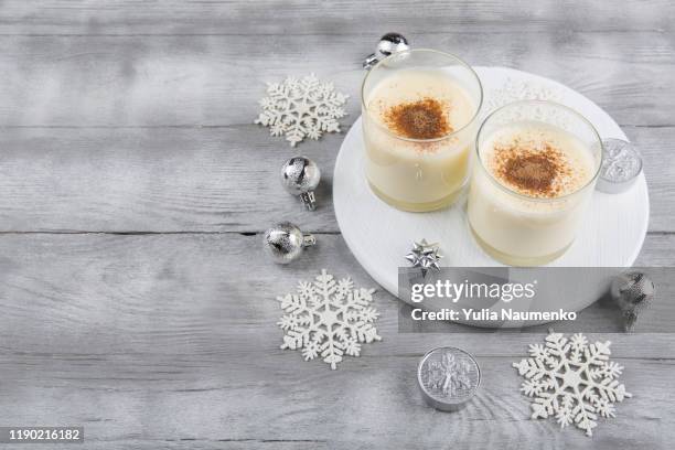 two homemade eggnog with cinnamon, christmas decorations on light wooden background. copy space. - eggnog stock pictures, royalty-free photos & images