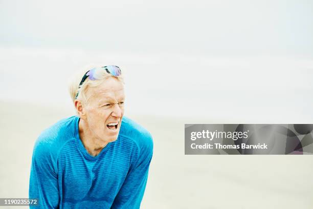 senior man breathing hard after early morning run on beach - boca aberta - fotografias e filmes do acervo