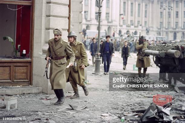 Romanian soldiers run in the debris of destructed buildings during fights to overthrow the Socialist Republic of Romania, on December 24, 1989 in...