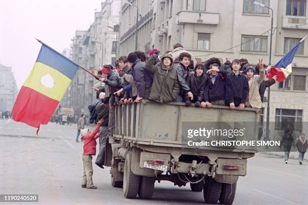 Young Romanian people drive on a military truck brandishing the Romanian flag through the streets of Bucharest during fights to overthrow the...