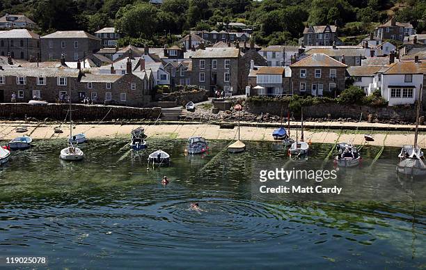 People swim in the harbour at Mousehole on July 14, 2011 near Penzance, England. With many state schools about to break for the summer holidays many...