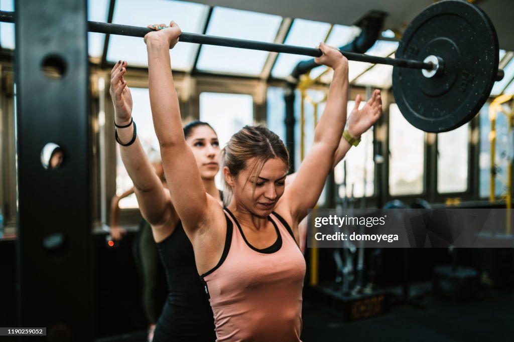 Two young women lifting weights in the gym