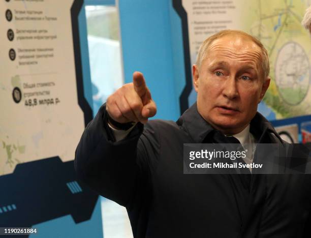 Russian President Vladimir Putin points while visiting the exhibition after riding a train across the bridge linking Russia and Crimean Peninsula at...