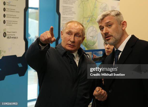 Russian President Vladimir Putin points as Transport Minister Yevgeny Dietrich while visiting the exhibition after riding a train across the bridge...