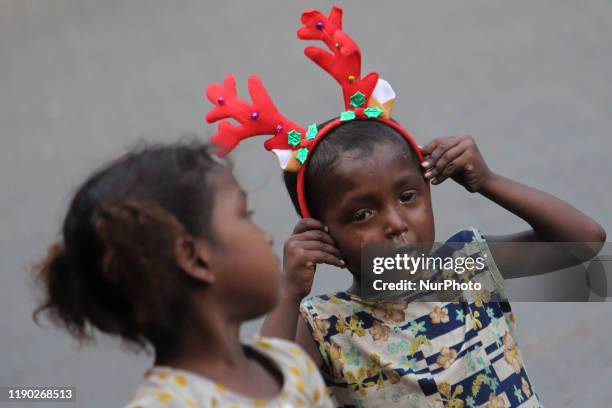 Homeless boy wearing a Christmas goodies looks on as he plays on a street in Mumbai, India on 23 December 2019.