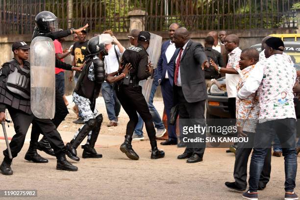 Riot policemen face members of Generations et peuples solidaires political party in front of the party headquarters in Abidjan on December 23 after...