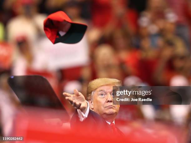 President Donald Trump tosses a hat into the crowd as he arrives to speak during a homecoming campaign rally at the BB&T Center on November 26, 2019...