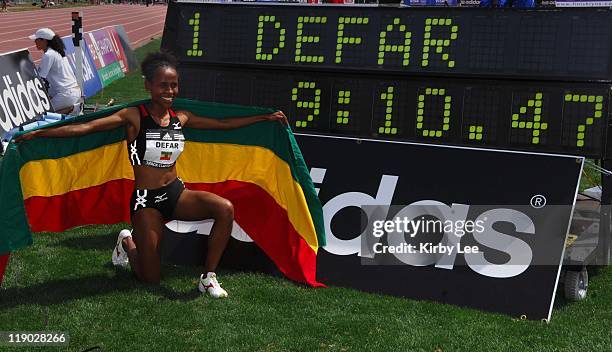 Meseret Defar poses with Ethiopian flag and the finish clock after setting a world-best in the women's 2-mile of 9:10.47 in the adidas Track Classic...