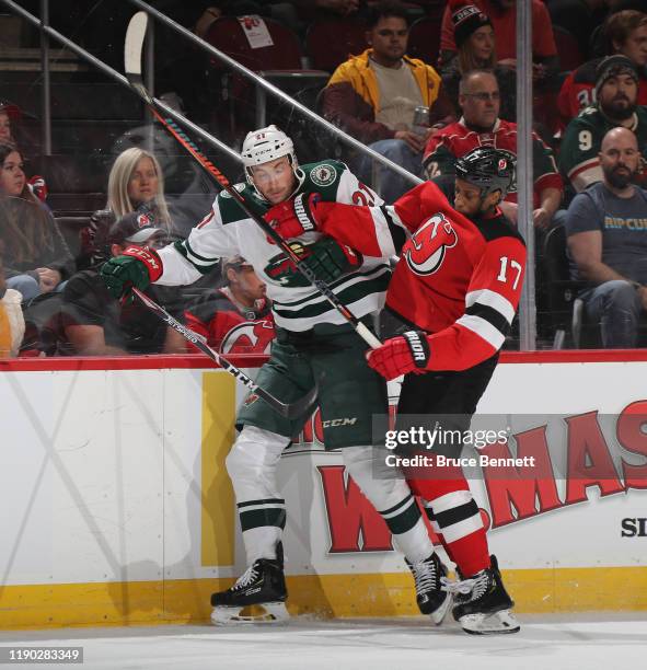 Wayne Simmonds of the New Jersey Devils checks Carson Soucy of the Minnesota Wild into the boards during the first period at the Prudential Center on...