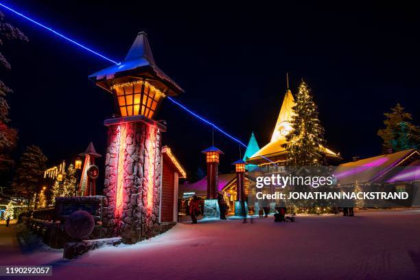 Picture taken on December 2, 2019 shows tourists next to a blue electric line at the Santa Claus Village that marks the border of the Arctic Circle...