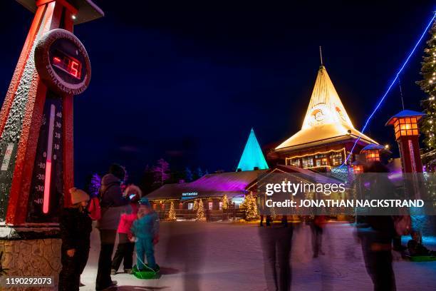 Picture taken on December 2, 2019 shows tourists next to a blue electric line at the Santa Claus Village that marks the border of the Arctic Circle...