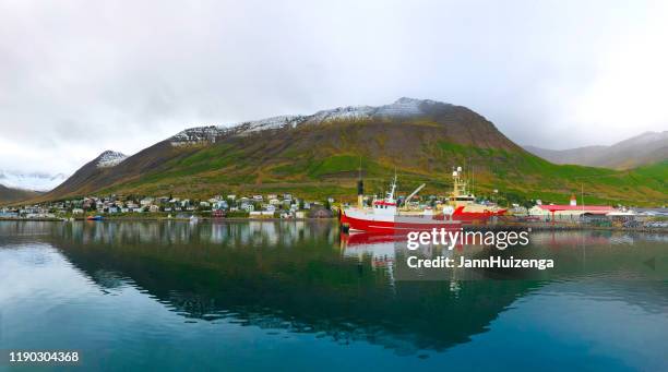 siglufjör-ur, island: trawler im fjordhafen, schneebedeckte grüne berge - fischerboot stock-fotos und bilder