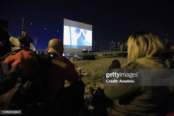 Iraqi youth attend an outdoor film screening at Tahrir beach in Baghdad, Iraq on December 23, 2109. Young protesters in Baghdad, continue to protest...