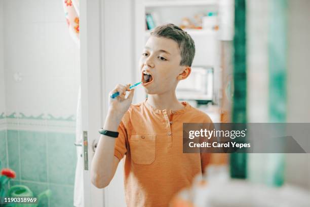 boy 11 brushing teeth in bathroom - man washing his teeth stock-fotos und bilder