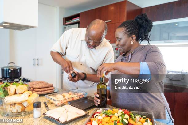 一緒に料理を楽しむシニアアフリカのカップル - middle aged couple cooking ストックフォトと画像