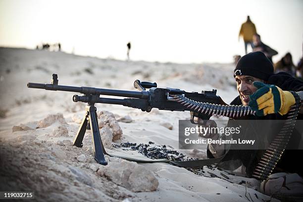 Libiyan rebel fires an M-60 machine gun towads pro-Gaddafi forces on Marcy 25, 2011 on the outskirts of Ajdabiya, Libya.