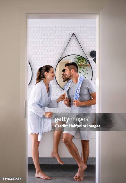 portrait of young affectionate couple standing indoors in bathroom at home, talking. - badezimmer mann stock-fotos und bilder