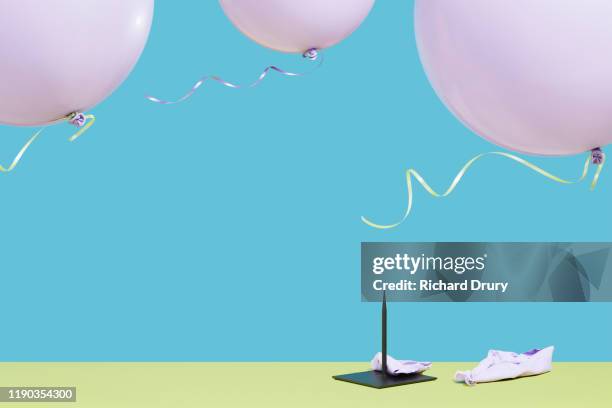 Three balloons flying over a metal spike with a burst balloon on the ground