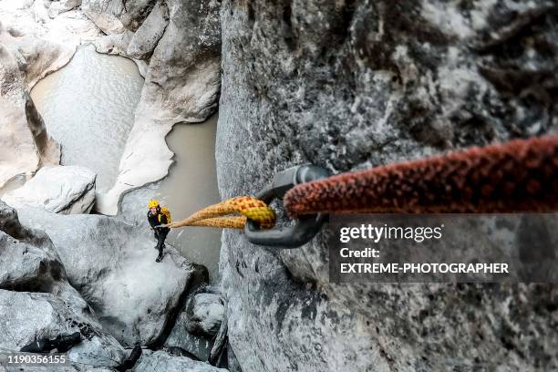 ein karabiner hält zwei statische seile zusammen. es gibt einen canyoneer auf der klippe unten ziehen am ende der unteren - karabiner stock-fotos und bilder