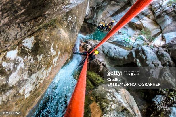 en hög vinkel bild av en canyoneer göra en nedstigning ner ett litet vattenfall i en kanjon - canyoning bildbanksfoton och bilder