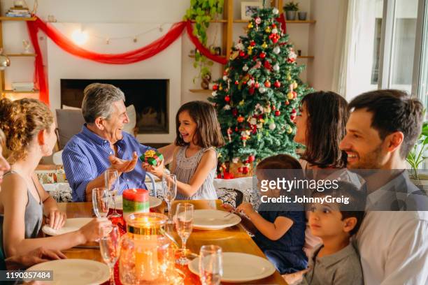 smiling young girl delivering christmas gift to grandfather - christmas tree close up stock pictures, royalty-free photos & images