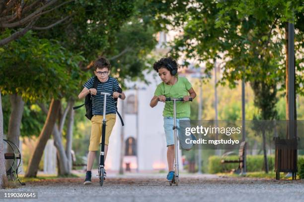 happy schoolboys riding with scooter in the city park with backpack - joy ride stock pictures, royalty-free photos & images