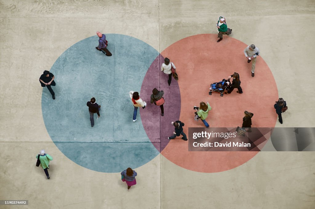 Pedestrians on a concrete floor with a blue and red Venn diagram.