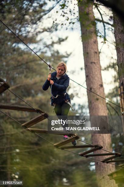 woman on high ropes activity course - scary rope bridge stock pictures, royalty-free photos & images