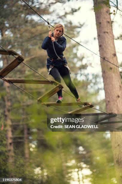 woman on woodland rope bridge - hangbrug stockfoto's en -beelden