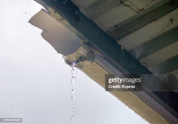 broken plastic gutter during rainstorm - grondaia foto e immagini stock