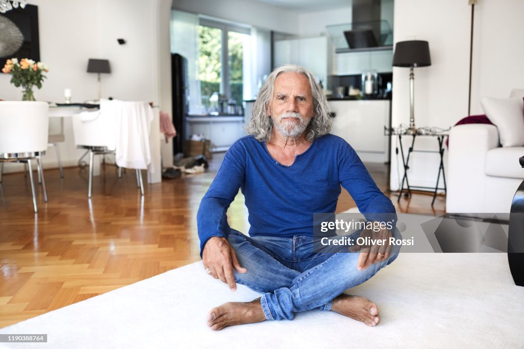 Portrait of senior man sitting on the floor at home