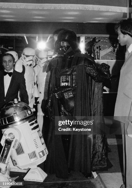 Actors dressed as fictional characters Darth Vader and R2-D2, who all appear in the Star Wars franchise, attend the royal premiere of 'The Empire...