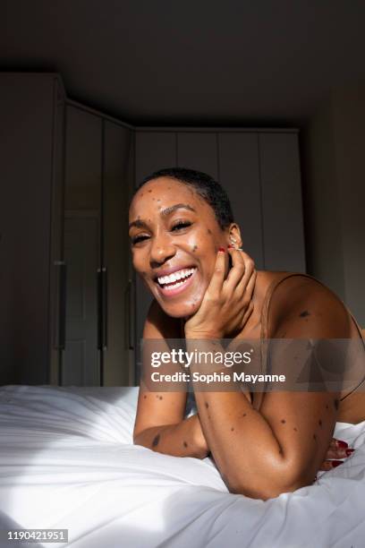 a portrait of a woman lying in her bed smiling - showus skin stock pictures, royalty-free photos & images