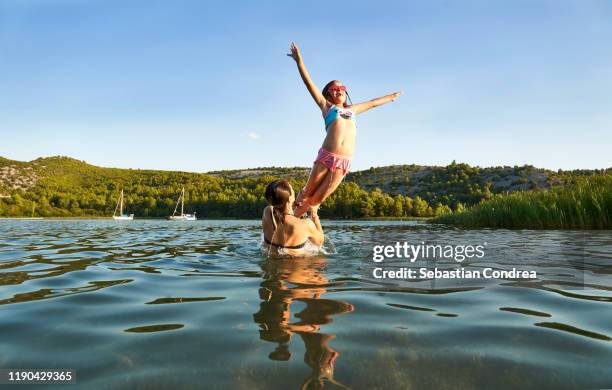 fun of a family of girls in the barn with swans, throwing the little girl up, krka national park, dalmatia, croatia travel, discovery europe - croatia girls fotografías e imágenes de stock