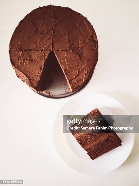 chocolate cake with avocado chocolate icing and a slice on a plate - gateaux foto e immagini stock