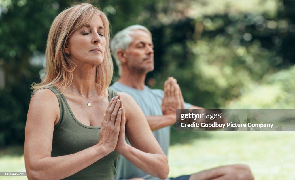 Reifes Paar meditieren zusammen während Yoga-Praxis draußen