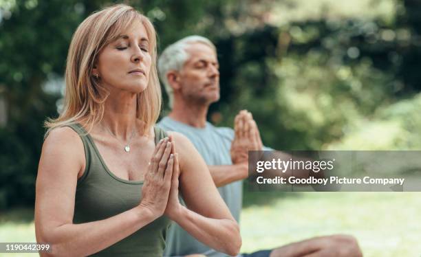 mature couple meditating together during yoga practice outside - ioga imagens e fotografias de stock