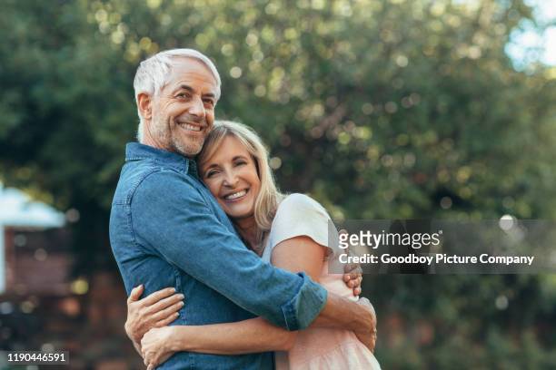 lächelnde reife paar affectionatley umarmt sich draußen - mature adult couple stock-fotos und bilder
