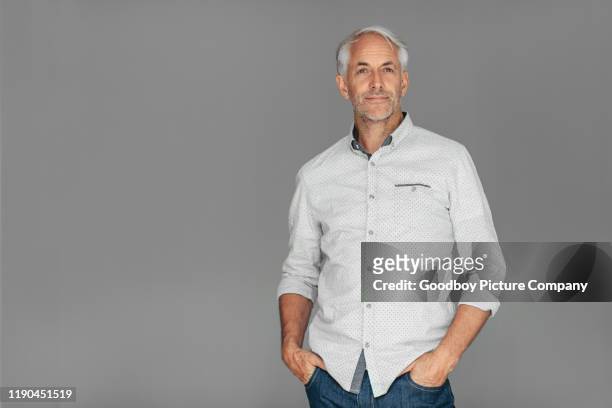 handomse uomo maturo in piedi su uno sfondo grigio - solo un uomo maturo foto e immagini stock