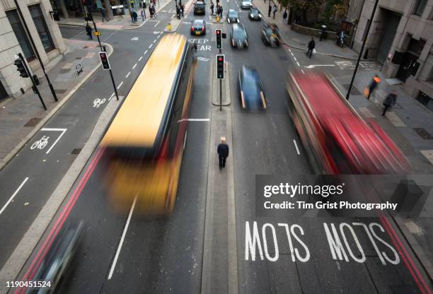 high angle view of blurred vehicles and man walking between traffic on a busy city street. london. uk. - road marking stock pictures, royalty-free photos & images