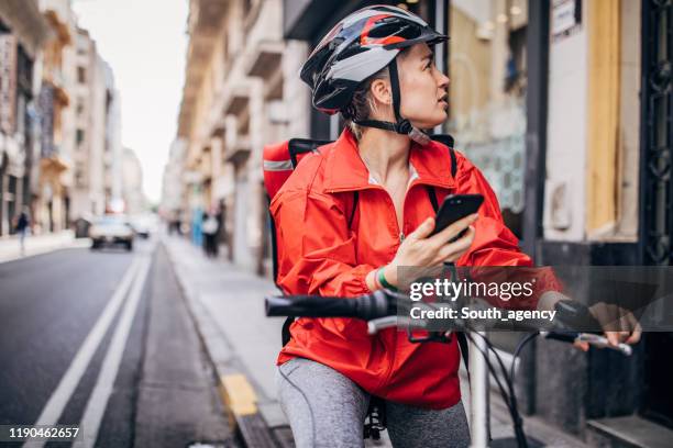 young delivery woman standing on the street - bike messenger stock pictures, royalty-free photos & images