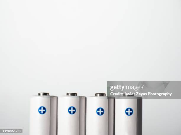 close-up of four aa rechargeable batteries against white background - lithium ion battery stock pictures, royalty-free photos & images
