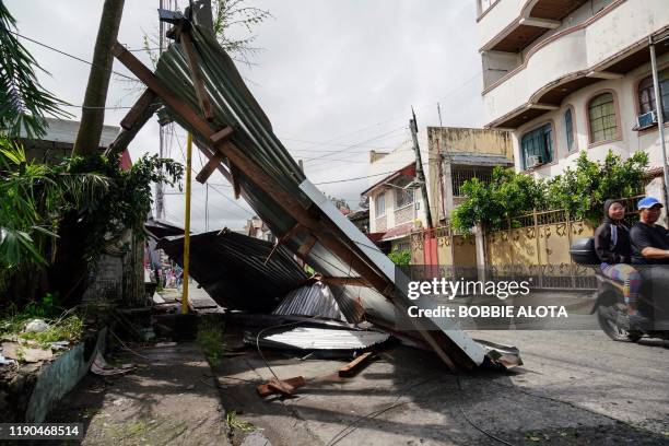 Motorist commutes past a blown down galvanised roof from a house damaged during the height of Typhoon Phanfone in Tacloban, Leyte province in the...