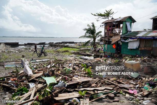 Residents walk past a house damaged during Typhoon Phanfone in Tacloban, Leyte province in the central Philippines on December 25, 2019. - Typhoon...
